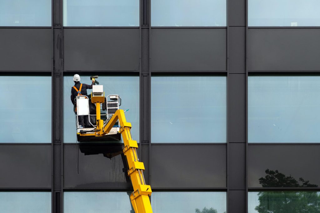Worker cleaning window on air lift platform