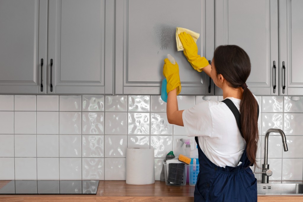 home cleaning service worker cleaning kitchen cabinet
